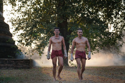 Full length of shirtless men boxing on land against sky