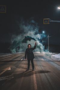 Full length portrait of man standing on street at night
