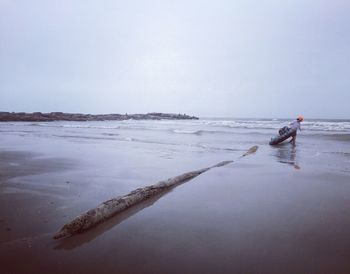 Man standing on snow covered beach against clear sky