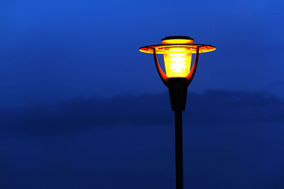 Low angle view of illuminated street light against blue sky