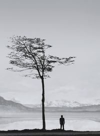 Silhouette man standing in front of lake against sky