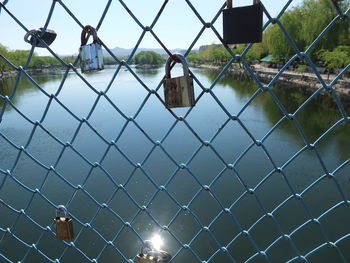 Padlocks on chainlink fence against sky