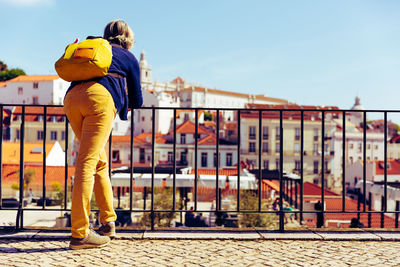 Rear view of woman standing by railing against sky