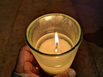 Close-up of hand holding tea light candle