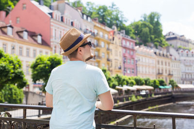 Man standing by railing in city