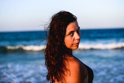 Portrait of young woman standing against sea