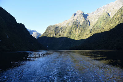 Scenic view of river amidst mountains against clear blue sky