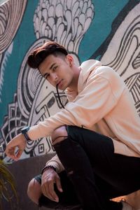 Full length portrait of young man sitting outdoors