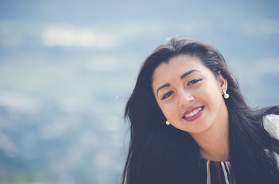 Portrait of smiling young woman against sky