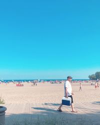 People on beach against clear blue sky