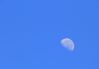 Low angle view of moon against blue sky