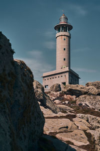 Low angle view of lighthouse amidst buildings against sky