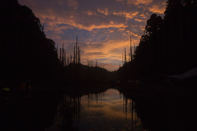 Silhouette trees by lake against sky during sunset