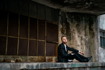Portrait of man sitting on building