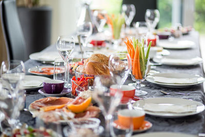 Cold cuts and fruits with vegetables amidst plates on table