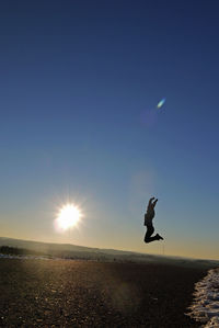 Silhouette man jumping on beach against clear sky
