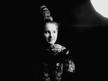 Portrait of young woman against black background