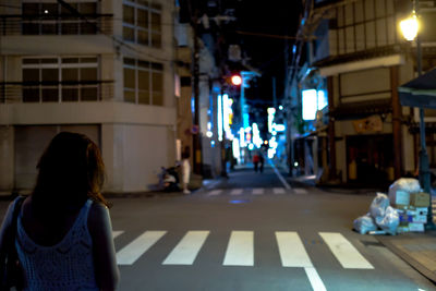 Rear view of woman walking on street at night