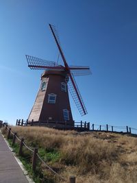 Traditional windmill on field against clear blue sky