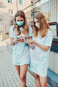 Midsection of woman holding mobile phone while standing outdoors