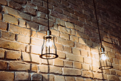 Low angle view of illuminated light bulb against brick wall