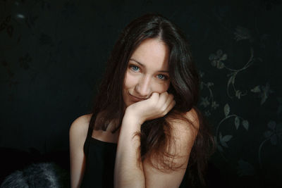 Portrait of young woman against black background