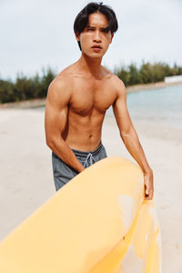 Portrait of shirtless man standing at beach