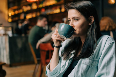Close-up of a beautiful brunette woman drinking coffee in a coffee shop.