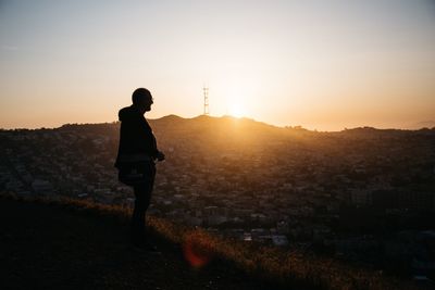 Silhouette of man with arms outstretched against sunset sky