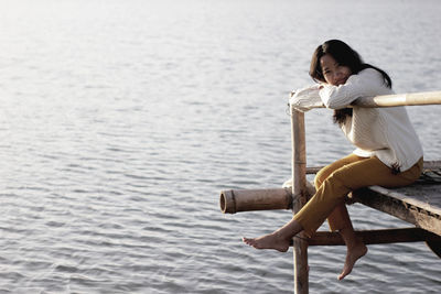 Full length of woman sitting on sea shore