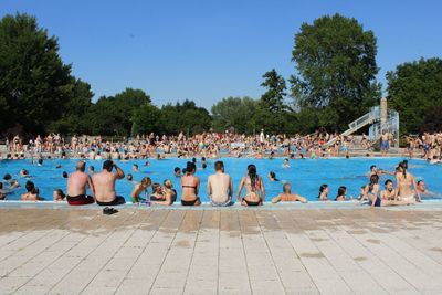 People at beach against clear blue sky