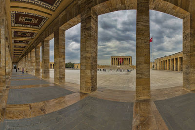 Corridor of historic building against cloudy sky