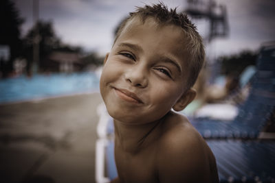 Close-up portrait of shirtless boy at poolside