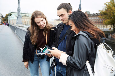 Friends standing on mobile phone in city