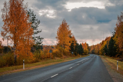 Road amidst trees against sky during autumn