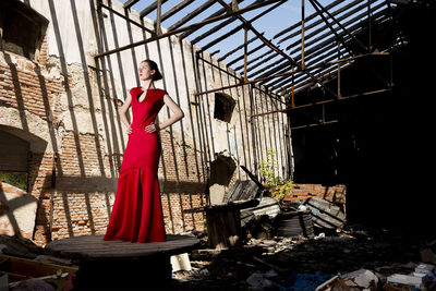 Full length of woman in dress standing on table in abandoned building