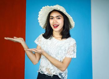 Young woman standing against blue wall