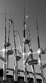 Low angle view of fishing rods  hanging against sky