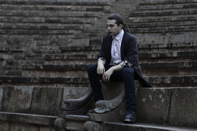 Thoughtful young man sitting on steps 