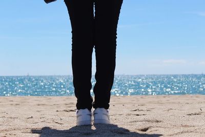 Low section of man standing on beach