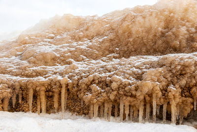 Lying pieces of ice on the seashore, icicles of different sizes, textures of sand 