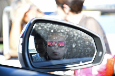 Reflection of couple in car side-view mirror