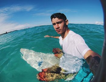 Fish-eye lens view of young man surfing in sea