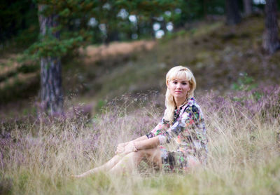 Portrait of young woman sitting by plants