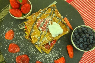 Homemade belgian waffles with berries on slate background. melted chocolate and whipped cream on