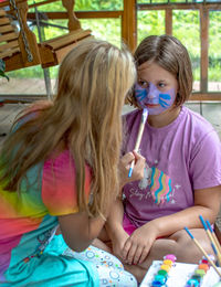 Sisters trust each other as they use face paint to decorate their faces