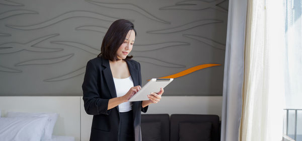 Young woman looking away while standing against wall