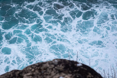 High angle view of waves splashing on rocks