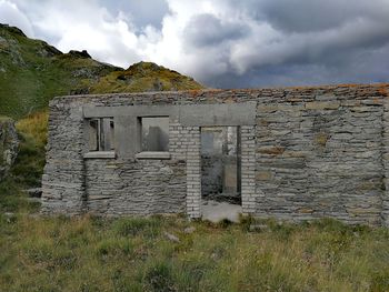 Old ruin building on field against sky