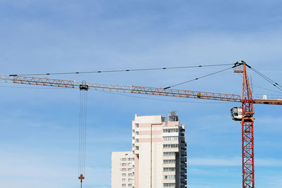 Low angle view of crane at construction site against sky